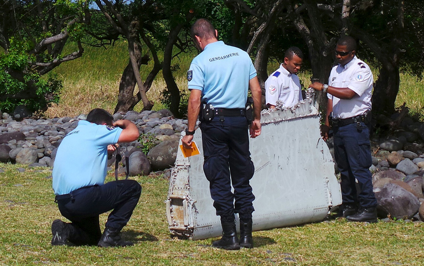 French gendarmes and police inspect a large piece of plane debris which was found on the beach in Saint-Andre, on the French Indian Ocean island of La Reunion, on Wednesday (Reuters photo)